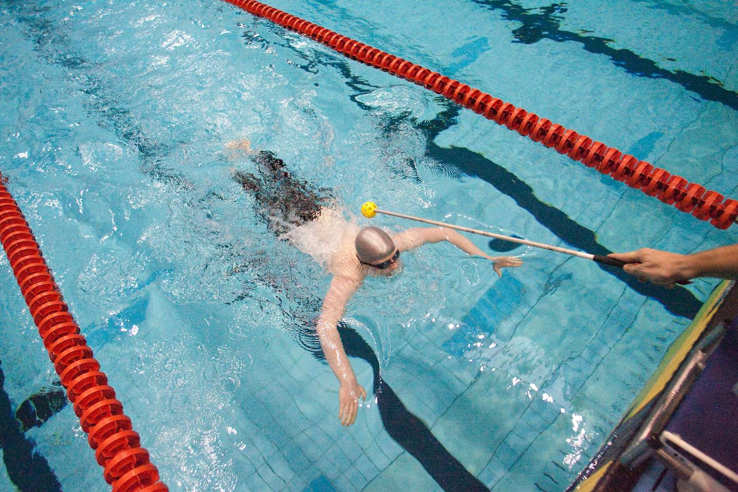 Visually impaired swimmer being tapped to turn