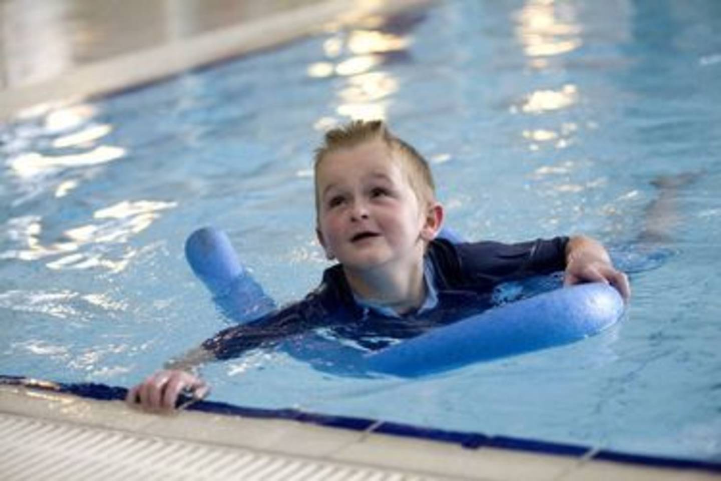 Young boy swimming in pool with float