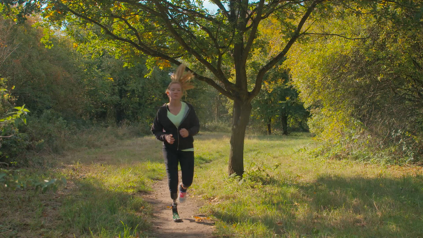 Cassie running in a park with her running blade on