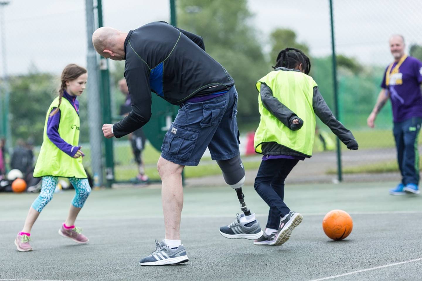 Man, who is is a leg amputee, playing football with children