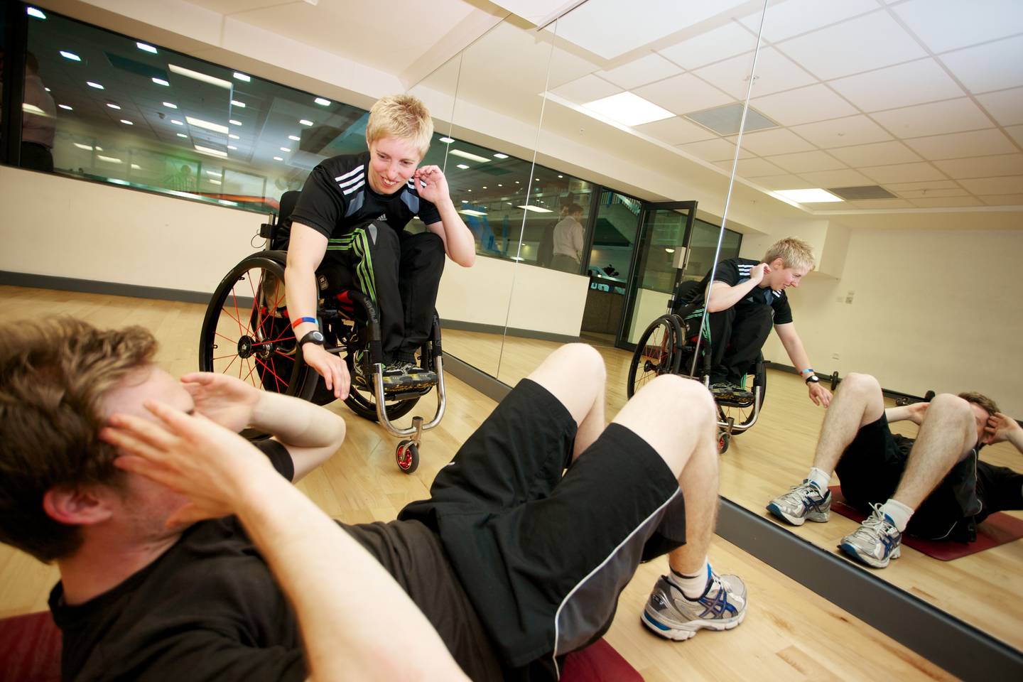 A gym instructor supports a gym user to exercise