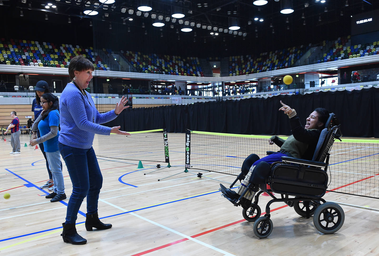 Girl in powerchair playing catch with supporter