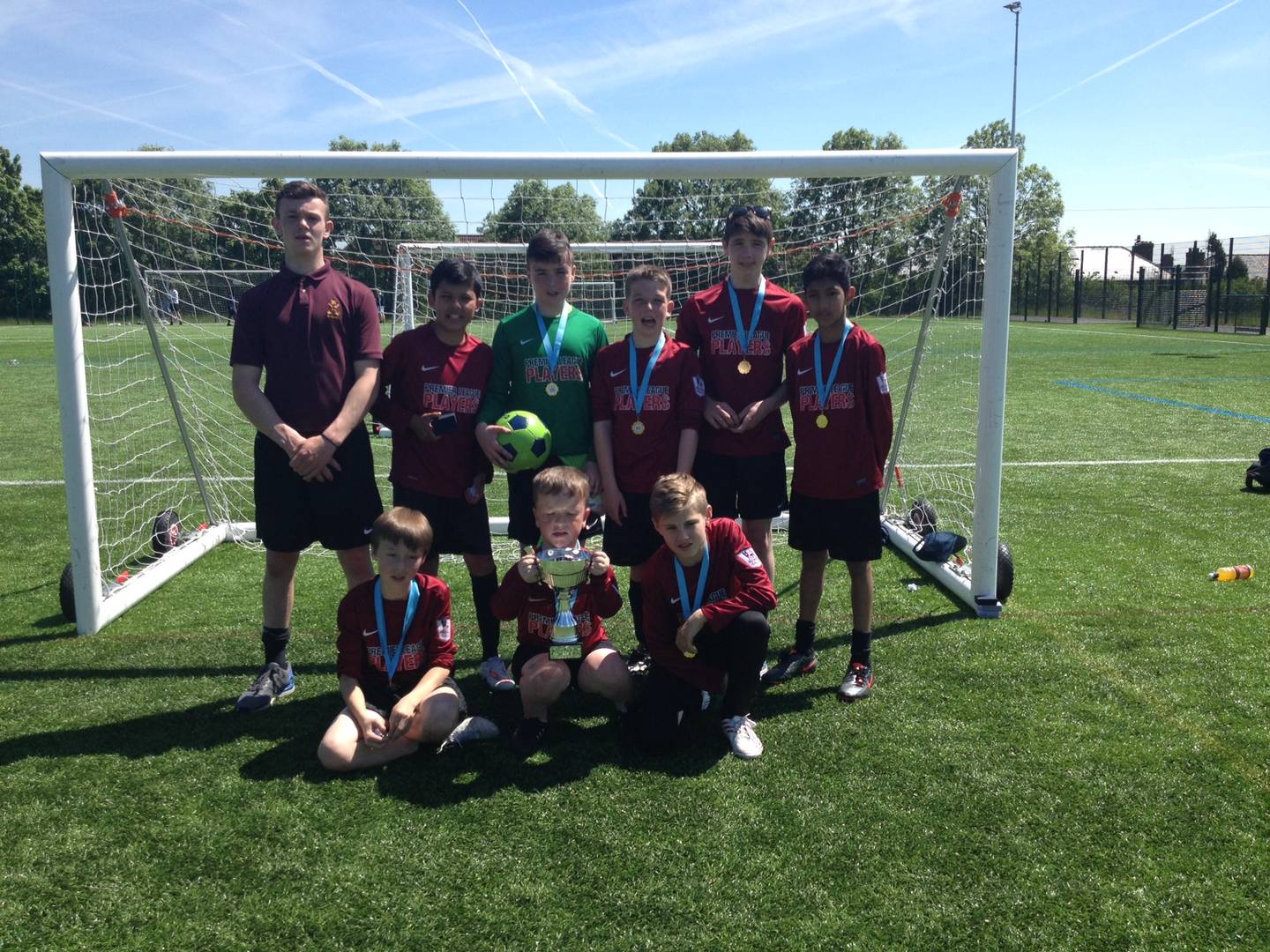 Asa and his football team on the pitch with their league trophy