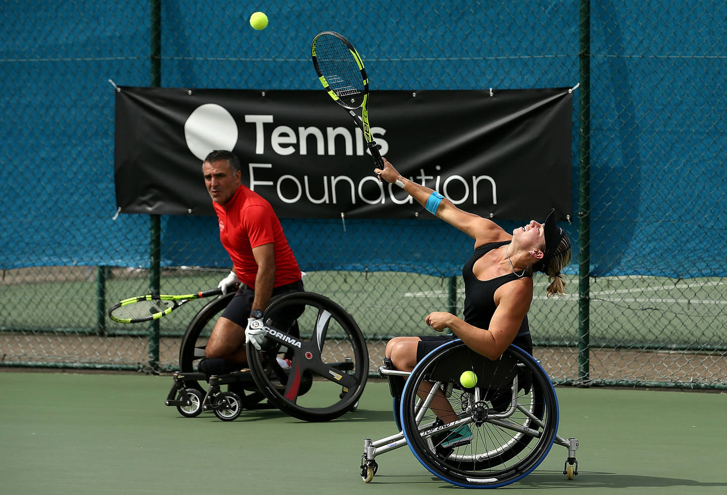 Lucy Shuker hitting serve in tennis match