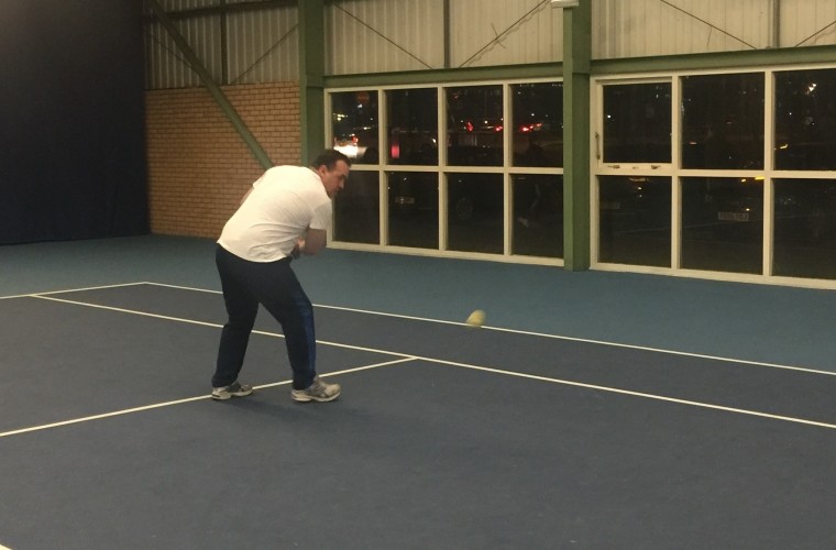 Matt playing a backhand shot on tennis court