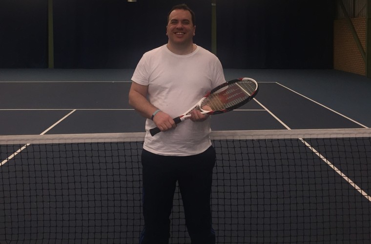 Matt standing by tennis net smiling to camera