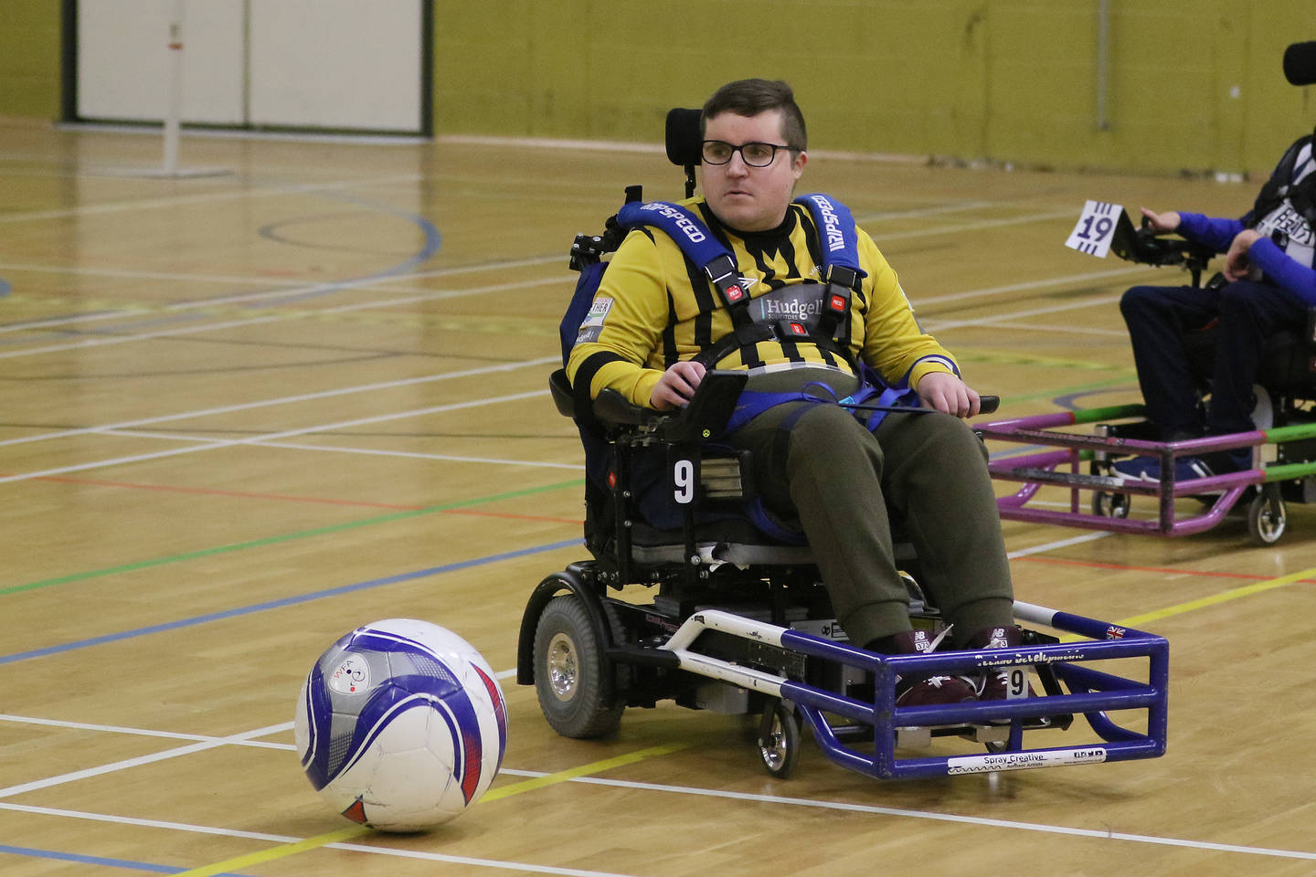 Powerchair football player playing a match in a sports hall. 