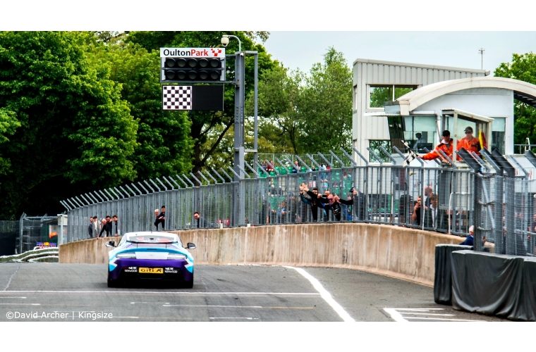 Team Brit racing car crossing finish line in race at Oulton Park race track