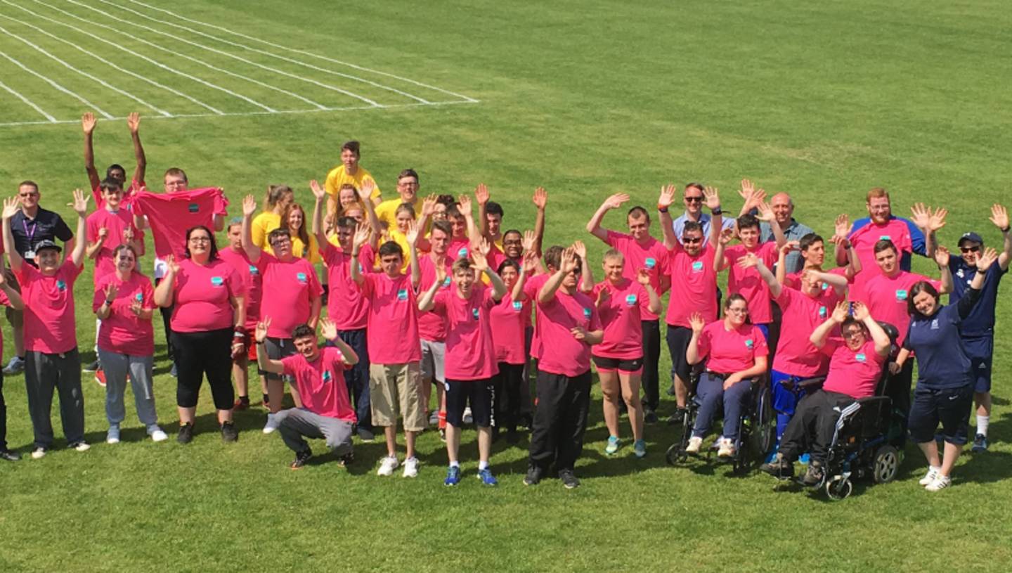 Group photo of disabled and non disabled students, teachers and staff on playing field.