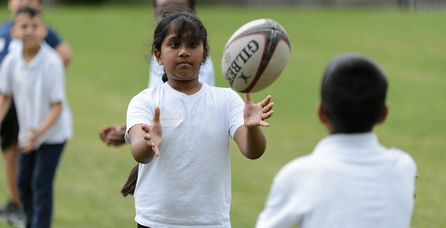 Girl catching rugby ball during school PE lesson