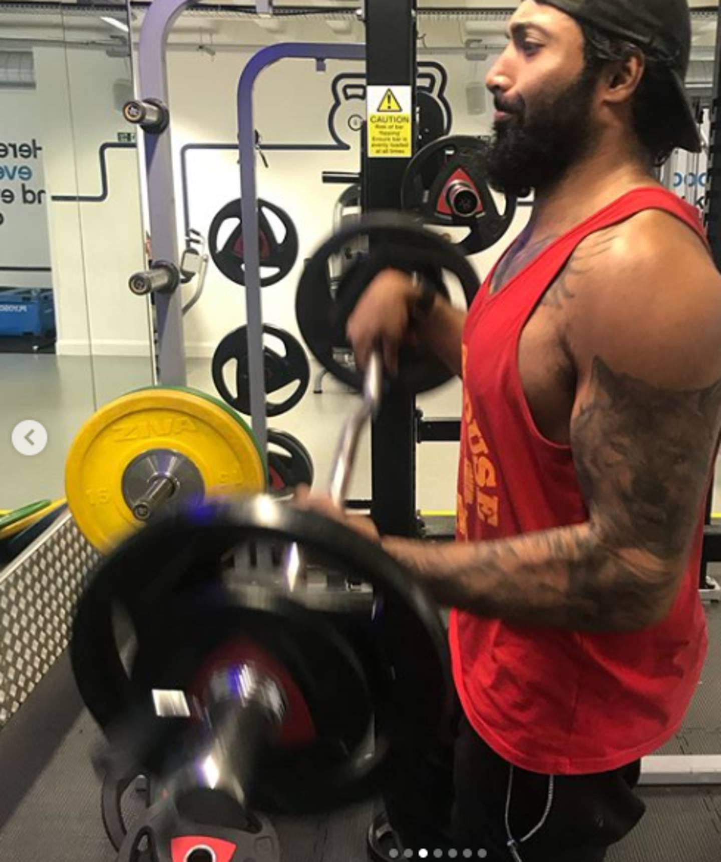 Shiraz doing bicep curls with barbell in the gym
