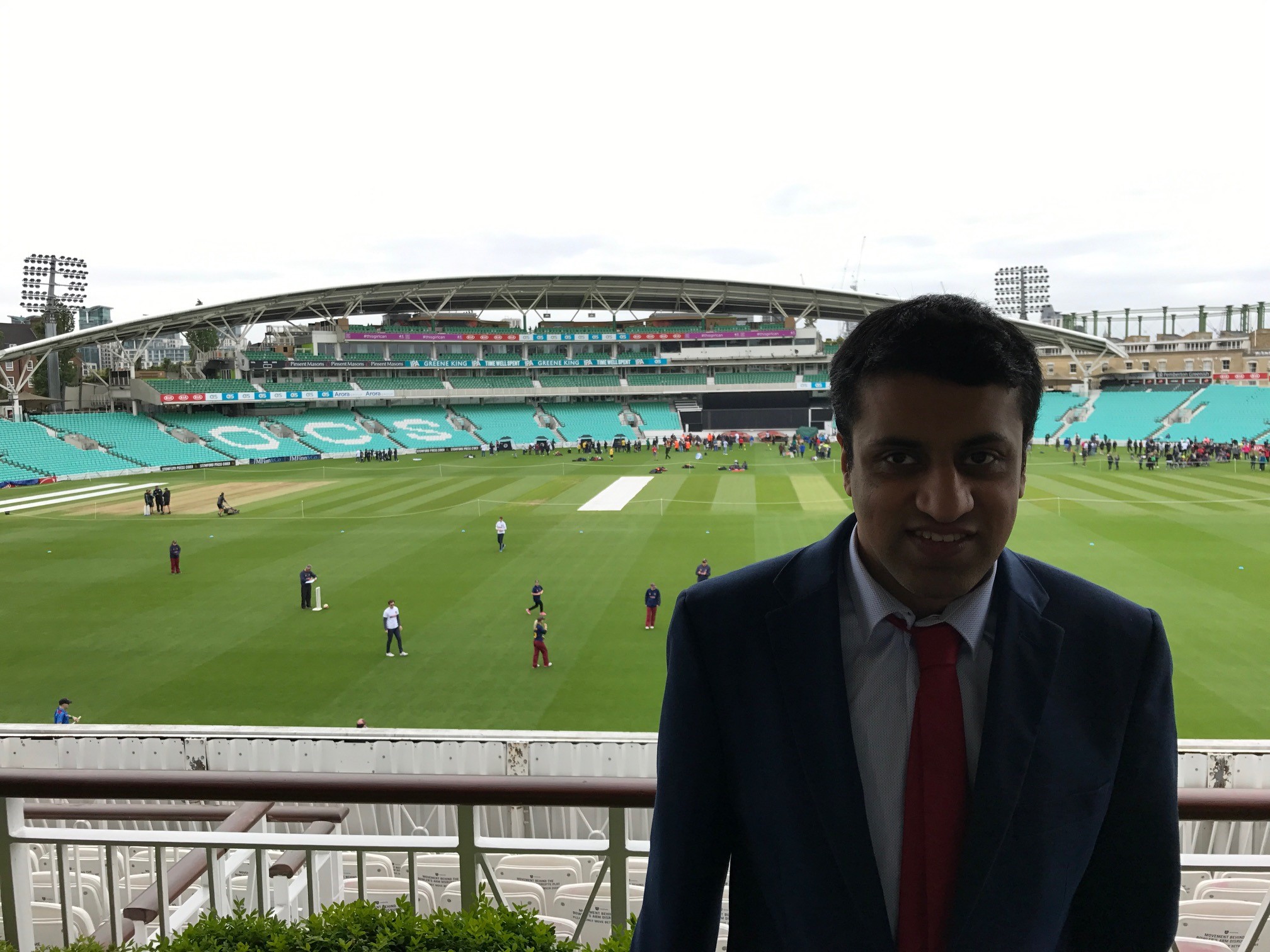 Hassan Khan in a suit with the Kia Oval cricket pitch in the background. 