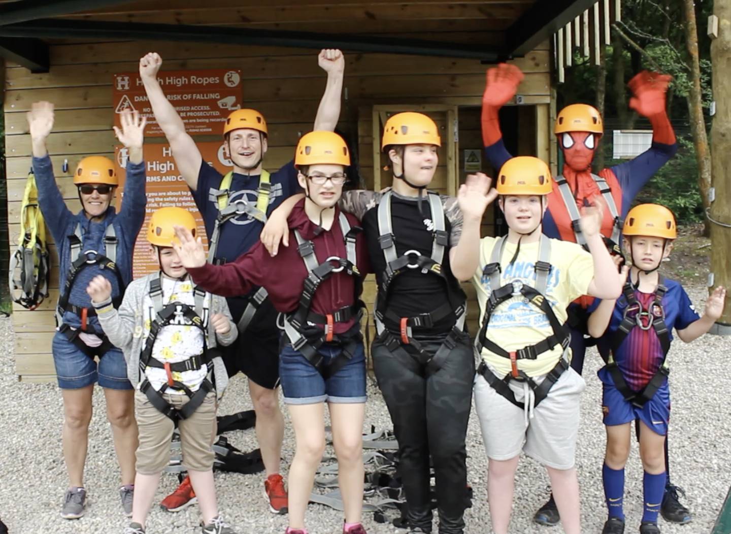 Children in climbing gear waving to camera. 