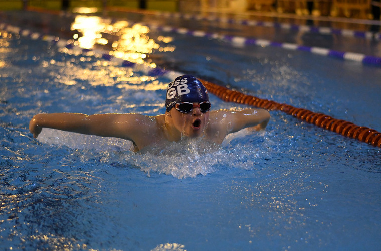 Zan swimming in pool with swimming cap and goggles on. 