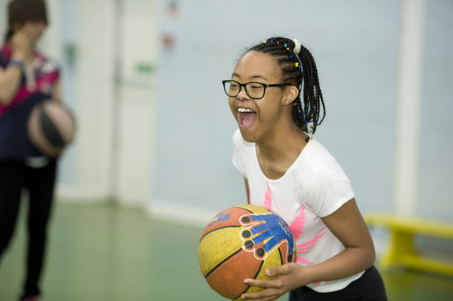 Young girl playing basketball in sport hall