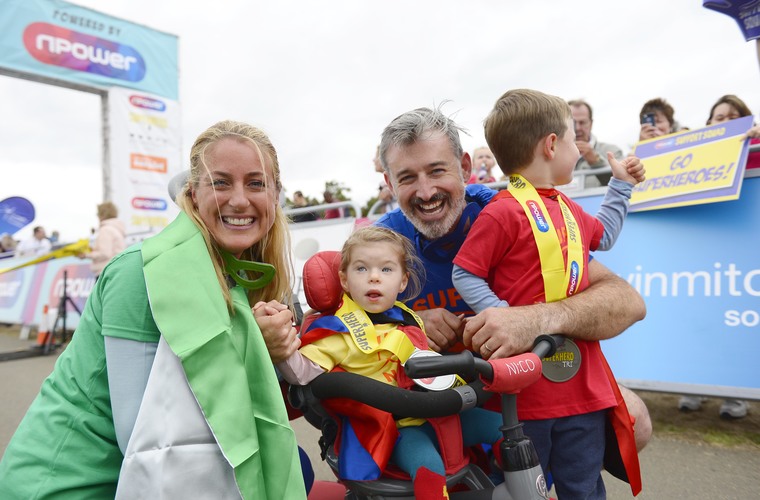 Family holding medals after finishing Superhero tri event