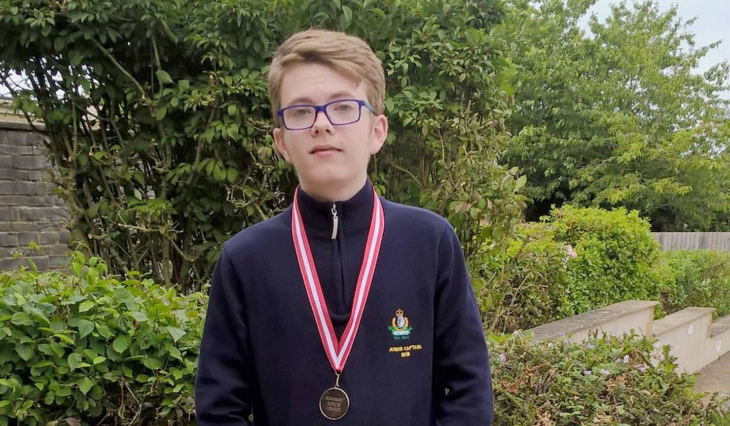 Tomas Wray young golfer, standing with a medal