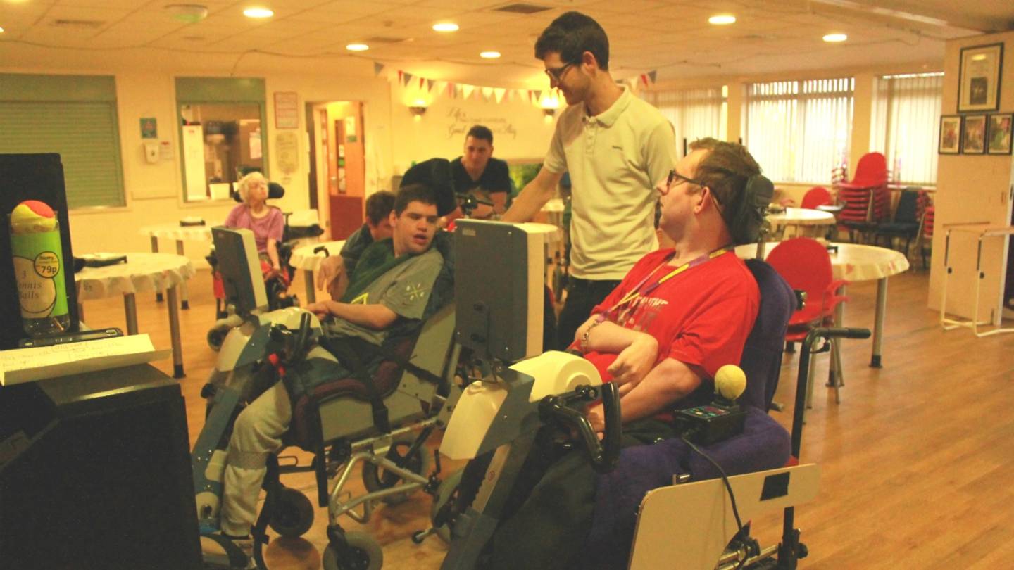 Physio Piers Baker supports two residents, Paul and Jamie, during a passive cycling relay race. 