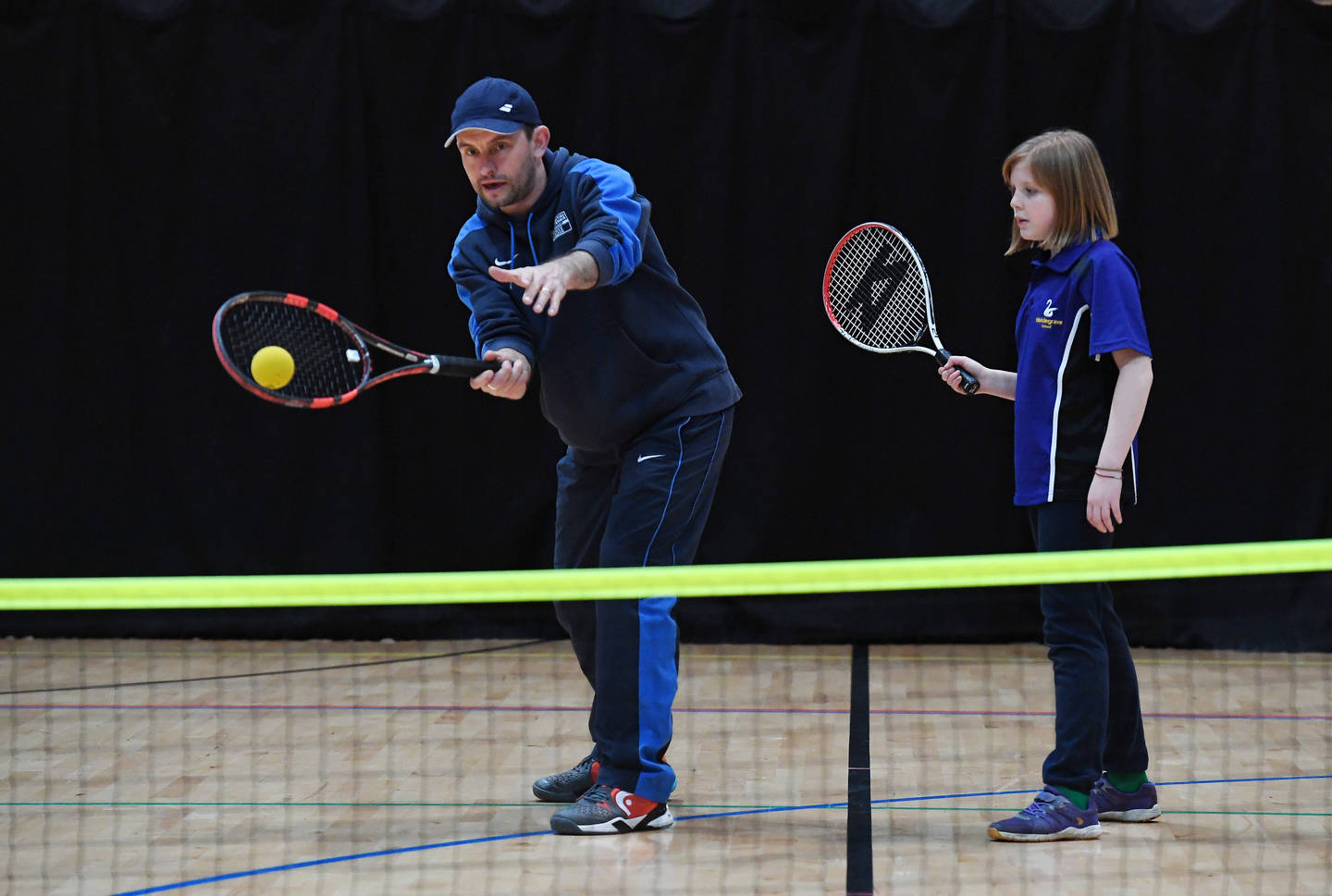 Tennis coach supporting young girl