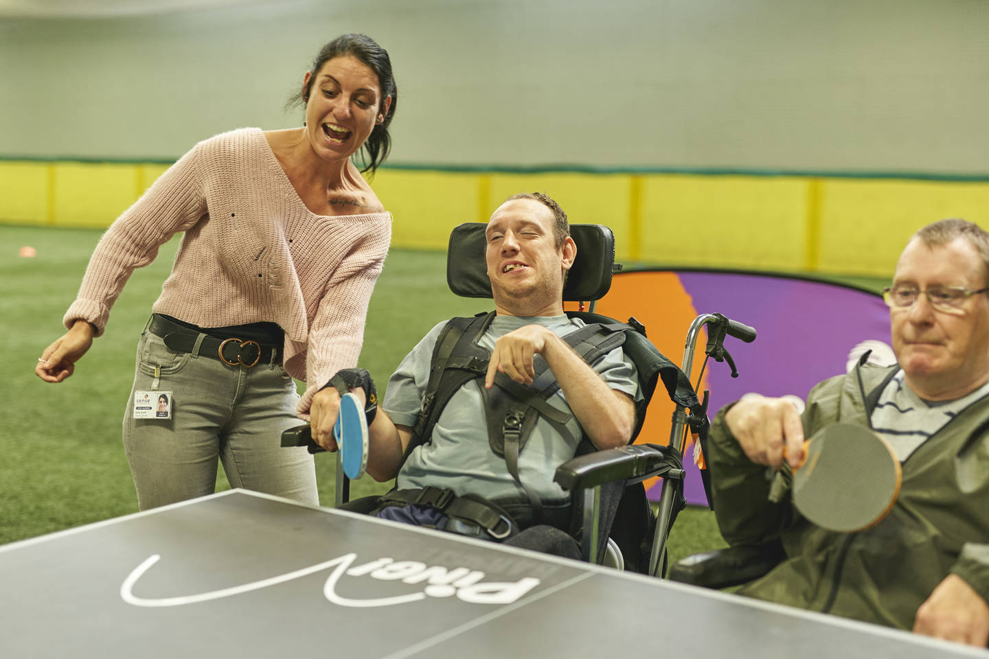 Two disabled men enjoying a game of table tennis with a supporter
