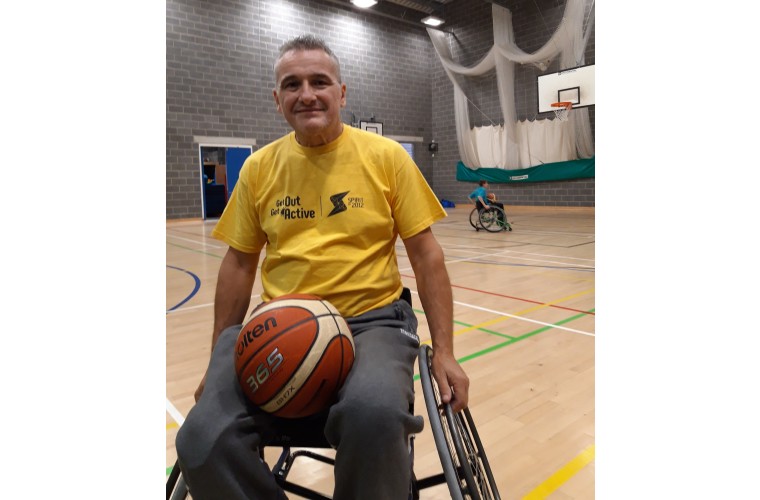 Adrian in sports wheelchair holding a basketball 