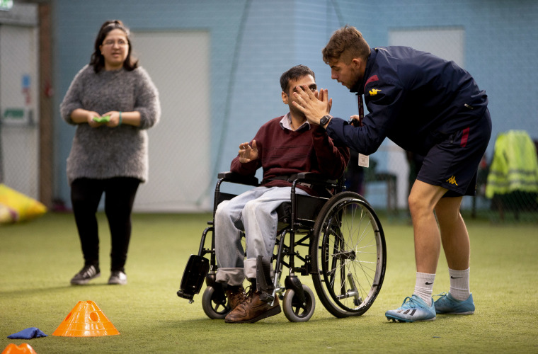 Man and football coach high five each other during inclusion activity session