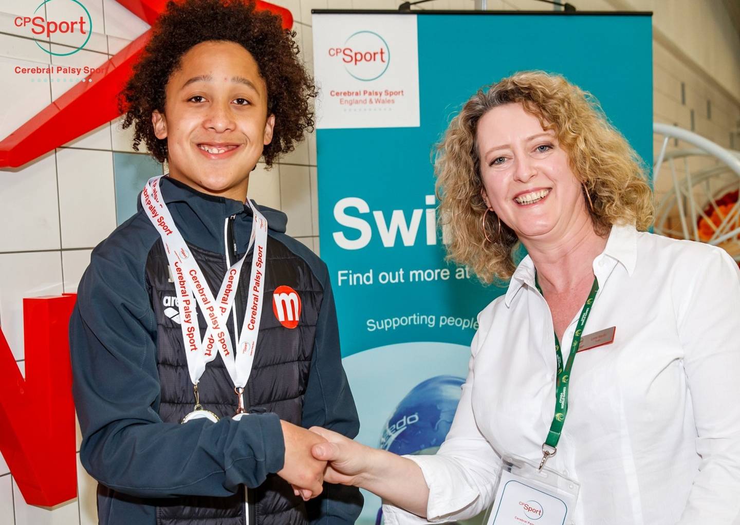 Lynne Wardle awarding a young swimmer with his medal at Swimming Championships