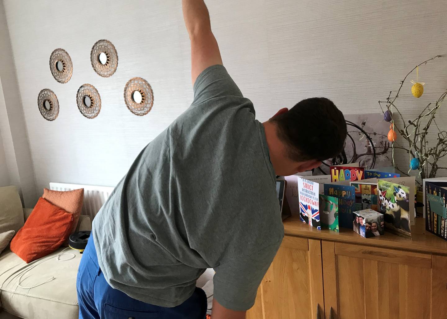 Image shows Ryan following online exercise class using his iPad in his living room