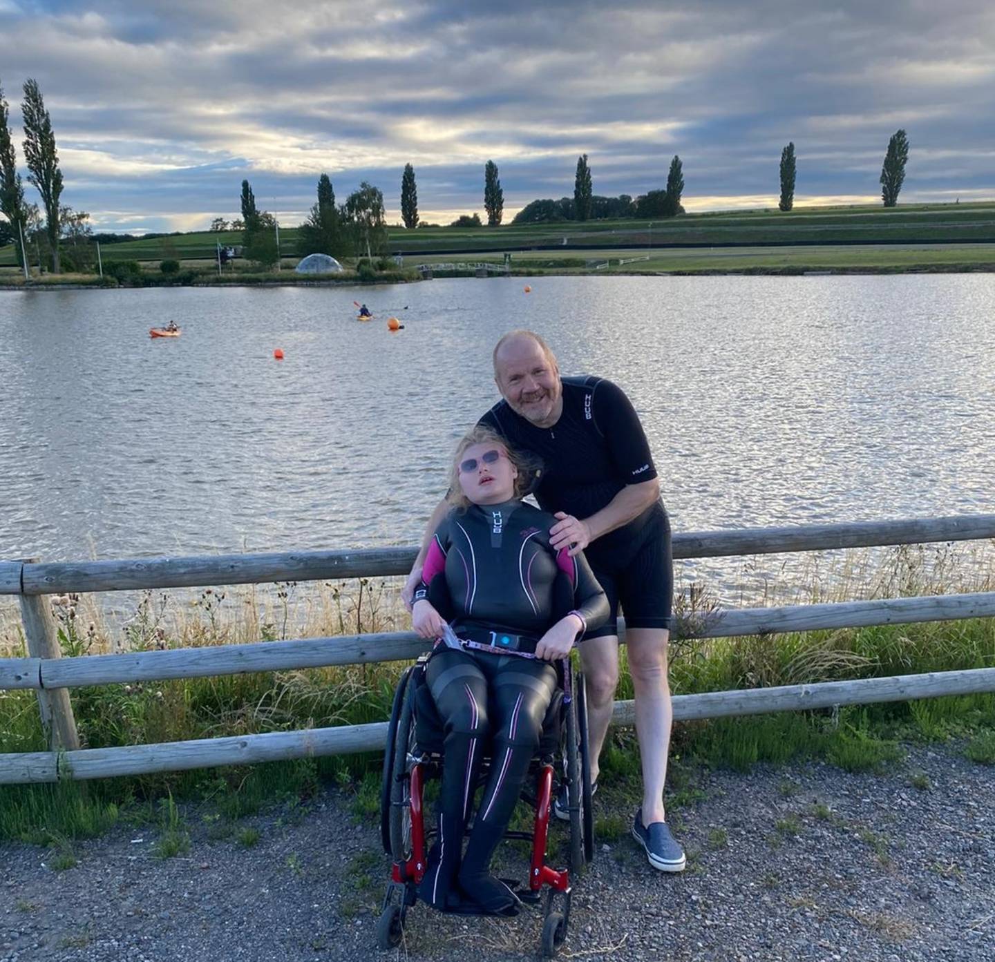 Stephan and Chloe smiling to camera with lake behind them. 