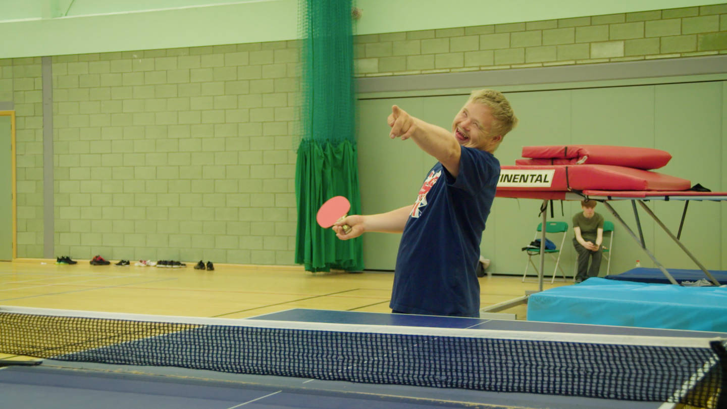 Young man smiling and playing game of table tennis 