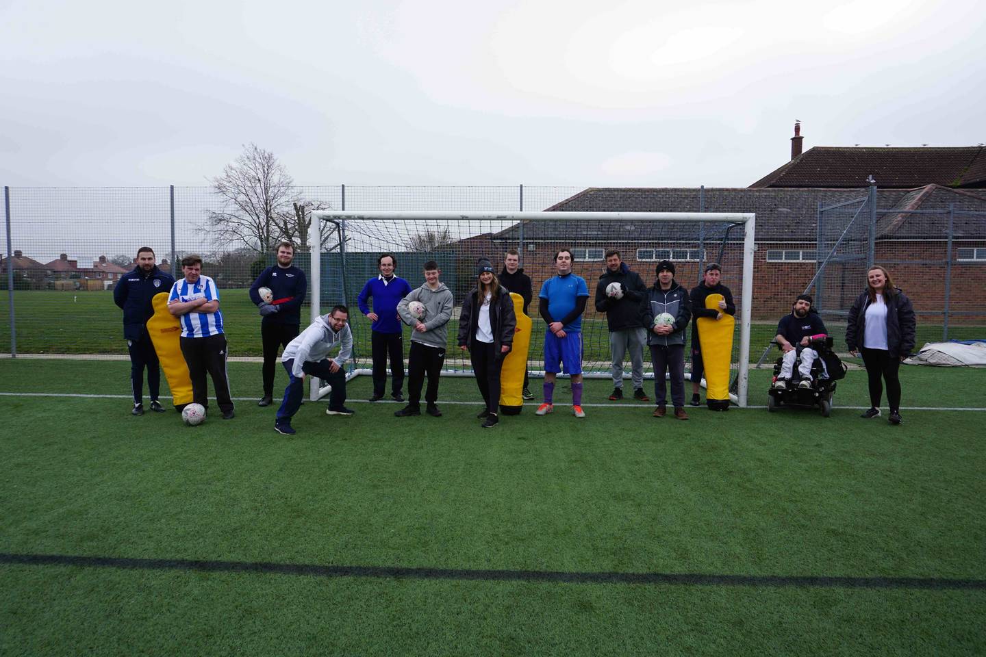 Group shot of Sport for Confidence and Colchester United FC on football field smiling to camera. 