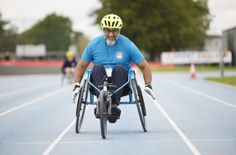 Disabled man taking part in wheelchair racing on an athletics track