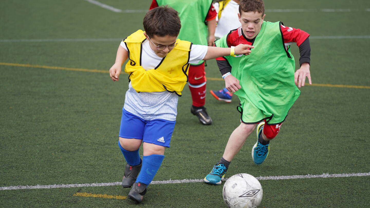Two young people with dwarfism playing football at National Dwarf Games