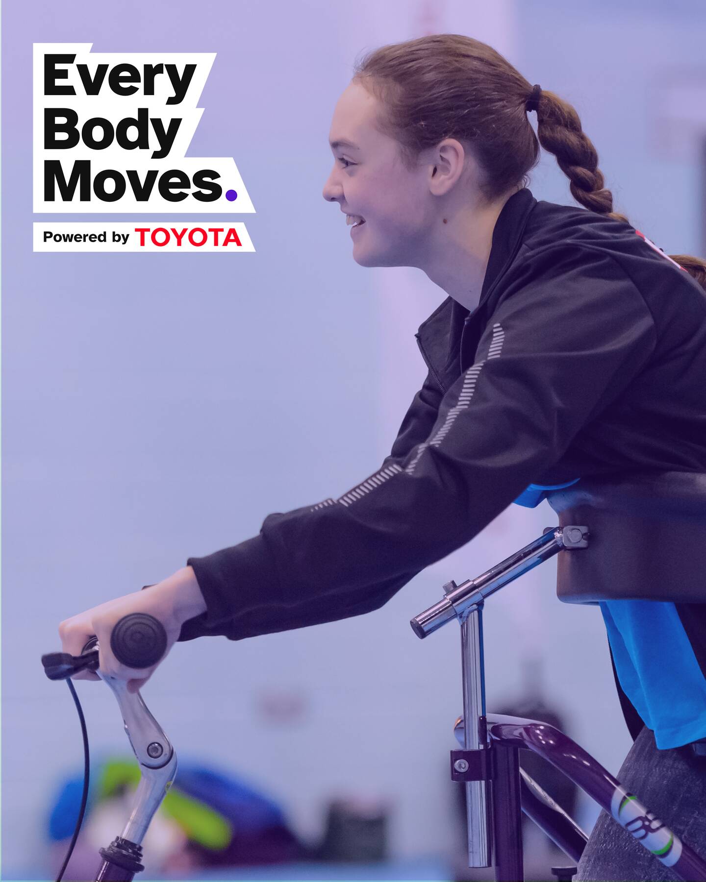 A woman smiles whilst holding a walking frame. The Every Body Moves logo is in the top left hand corner with the words Powered by Toyota underneath.