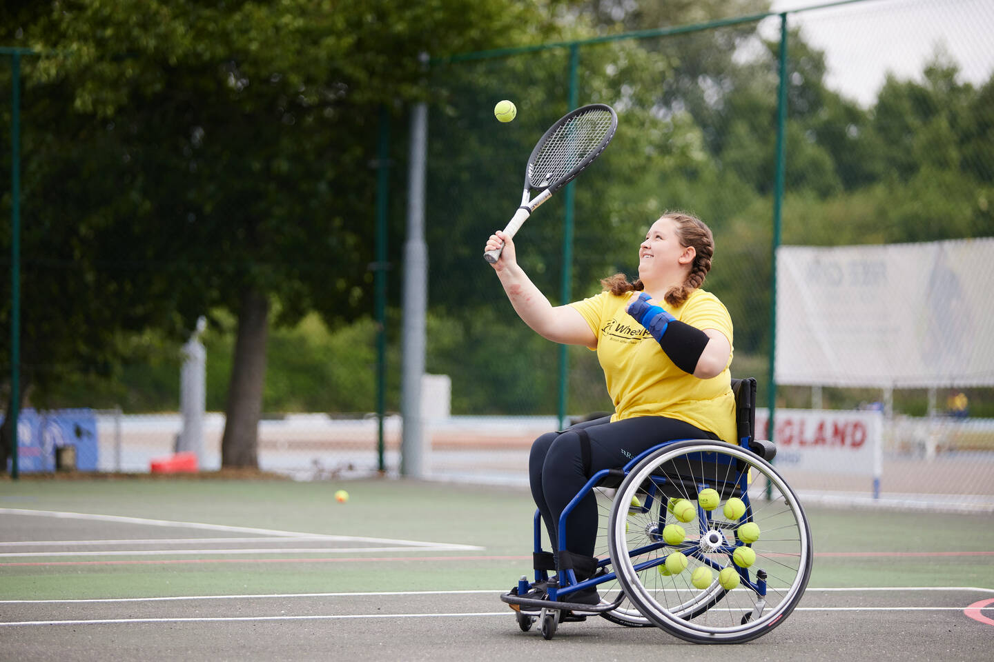 A girl serves whilst playing wheelchair tennis.