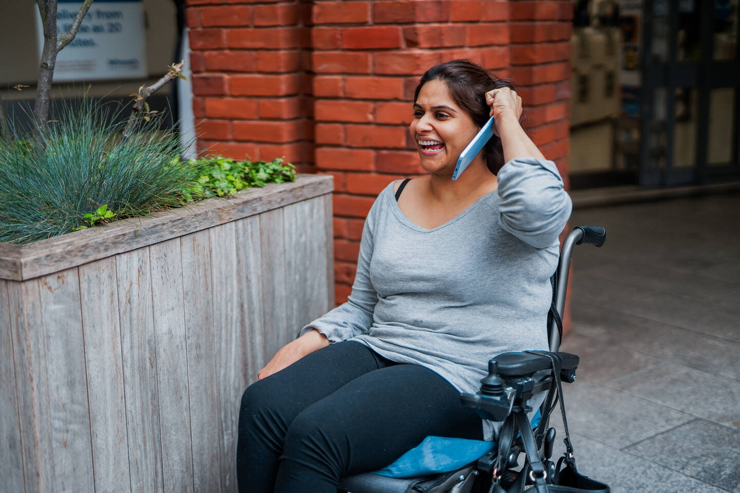A woman in a wheelchair uses the phone.