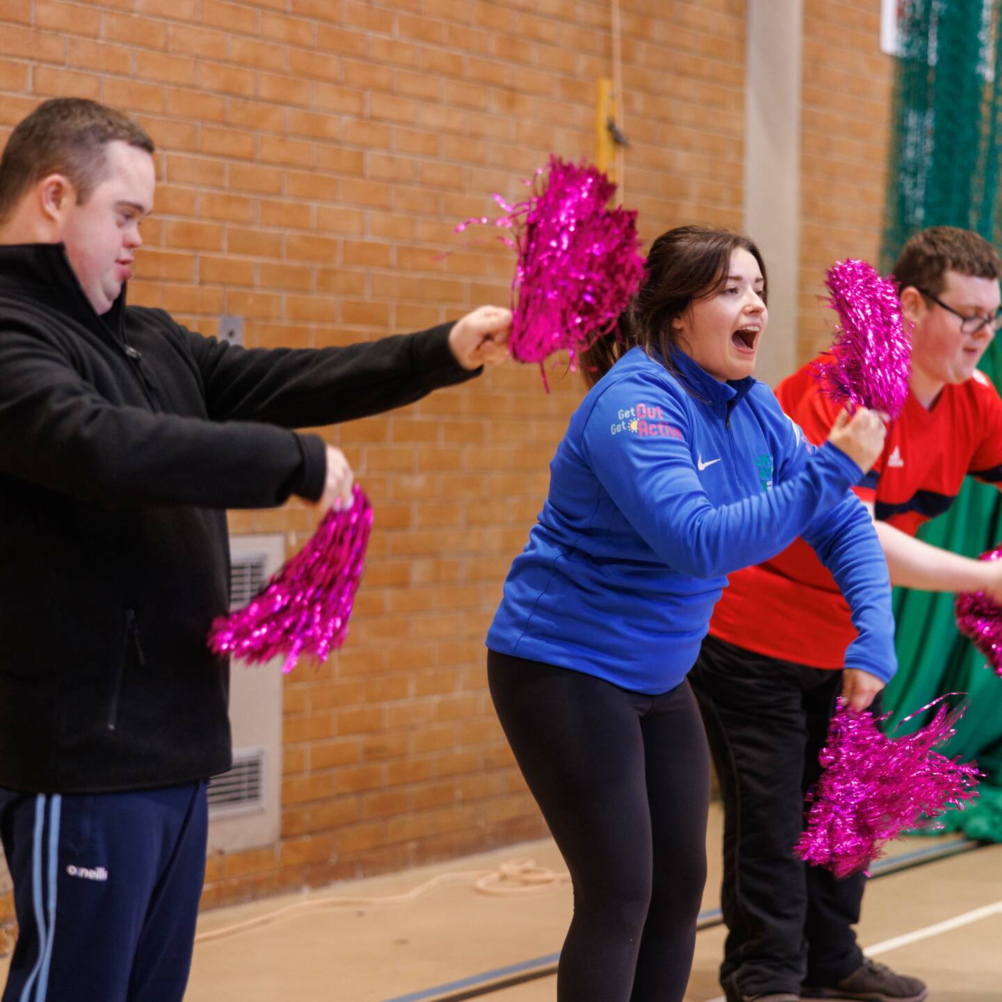Group of disabled and non-disabled people taking part in a dance session using pom poms. 