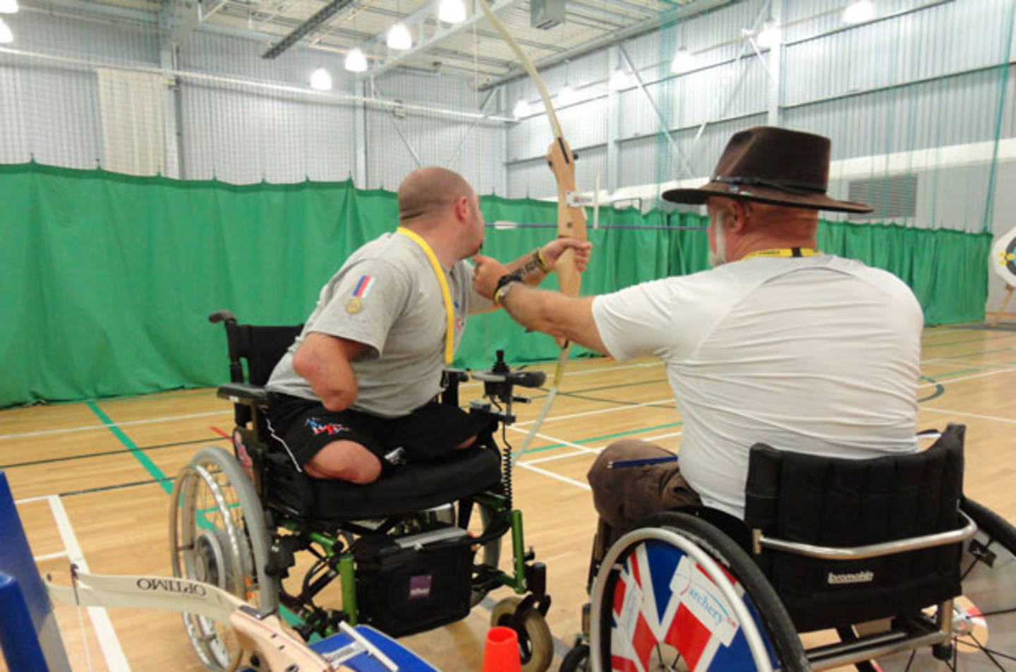 Image shows man in a wheelchair shooting an arrow in archery session