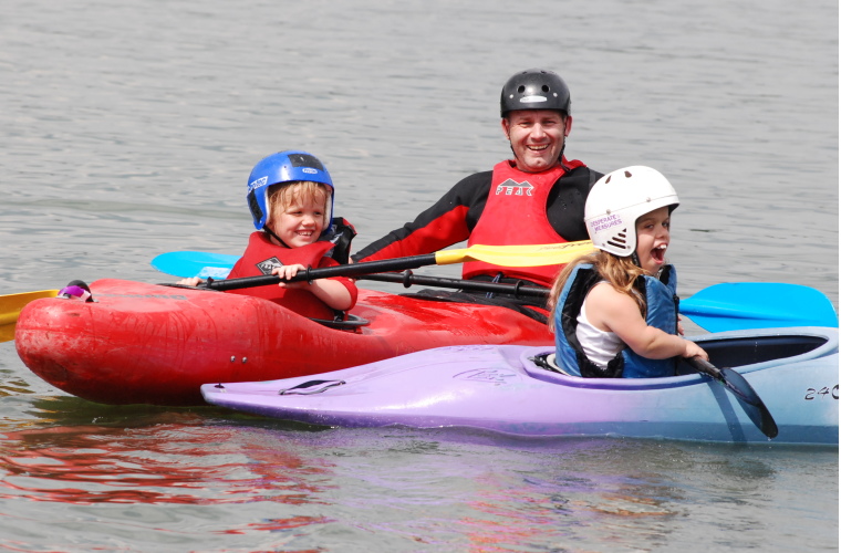 Two people with dwarfism canoeing with instructor