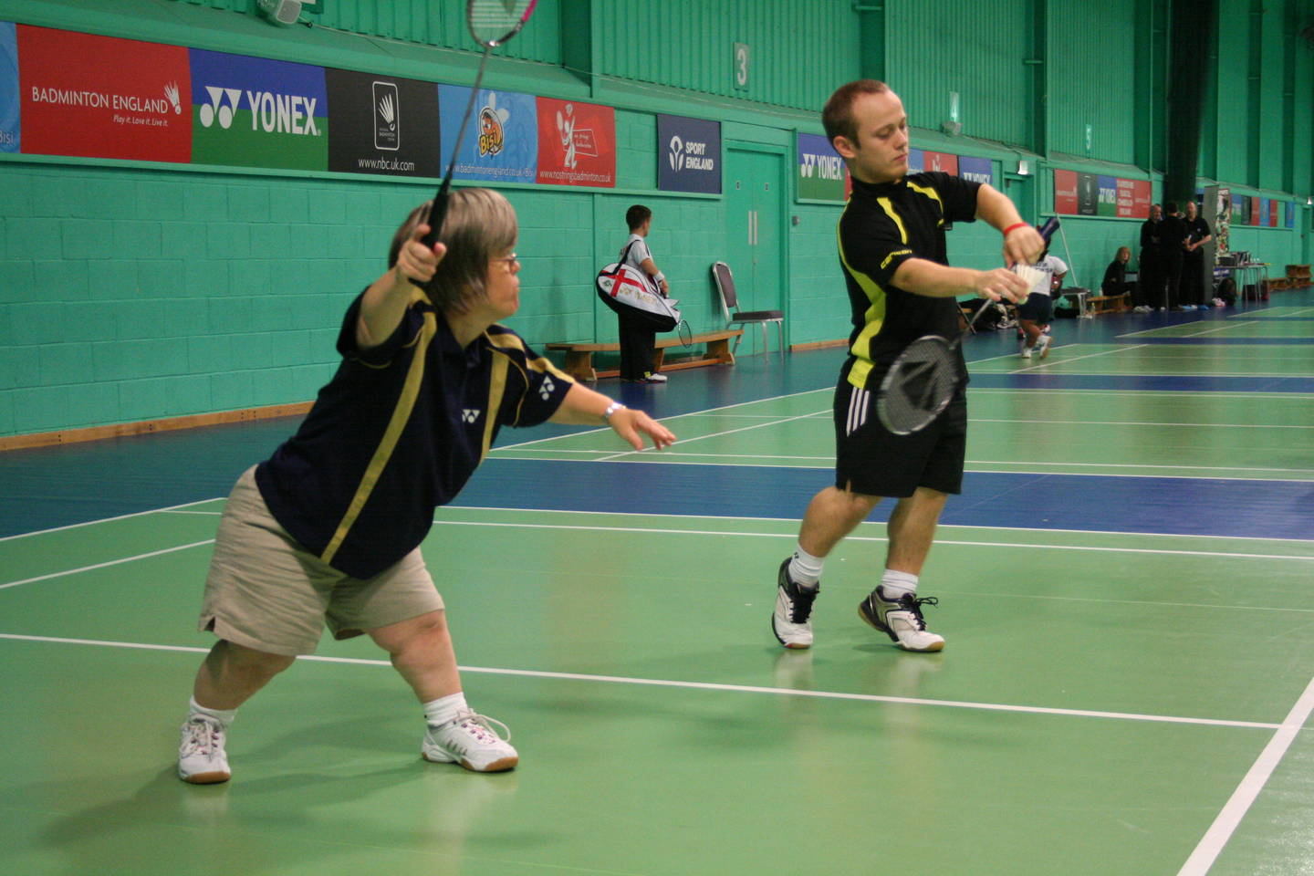 Man and woman with dwarfism playing mixed doubles badminton match