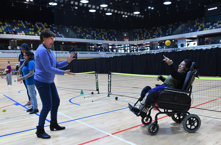 Girl in powerchair playing catch with supporter