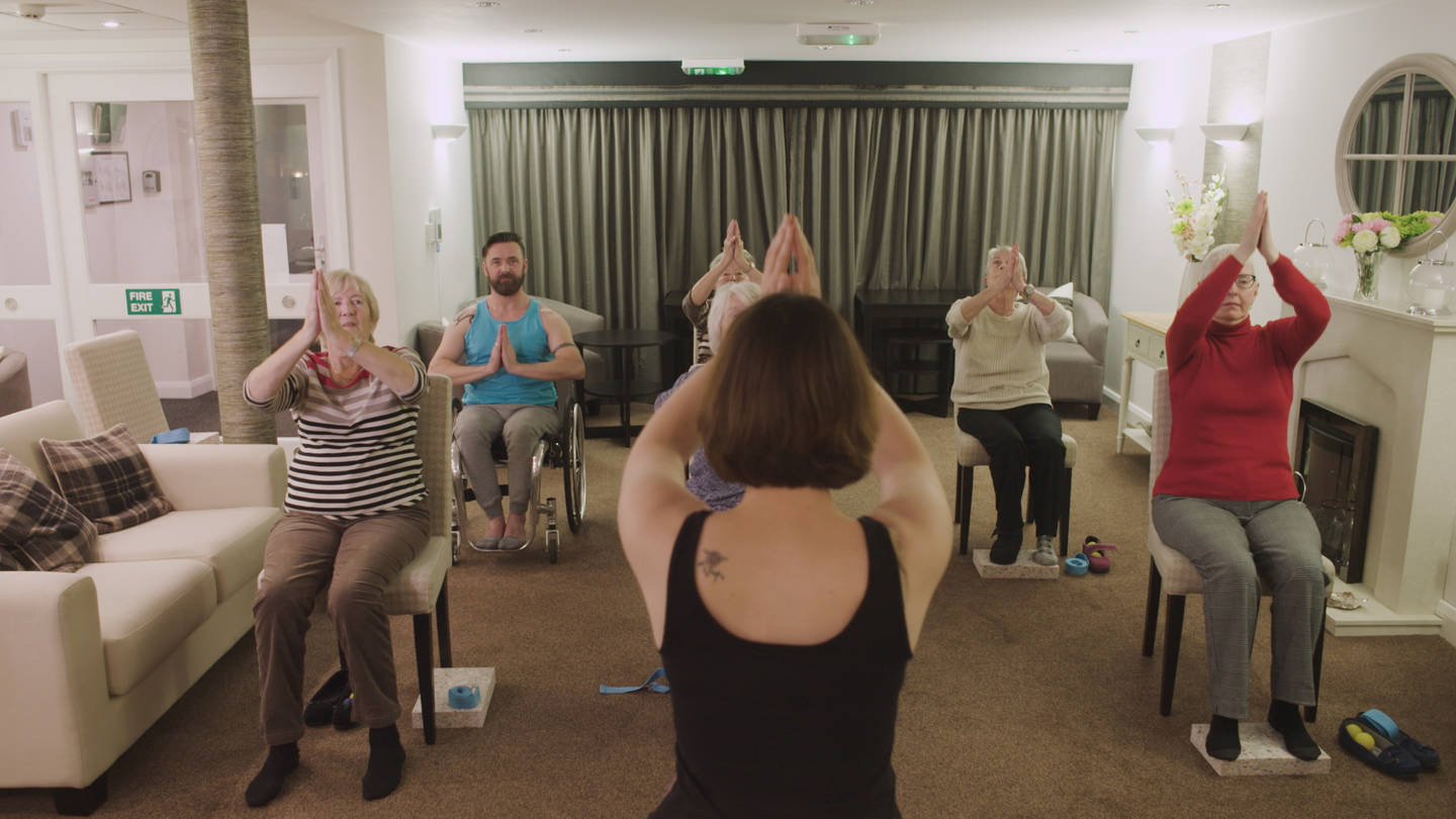 Presenter Kris taking part in a seated yoga session for older people