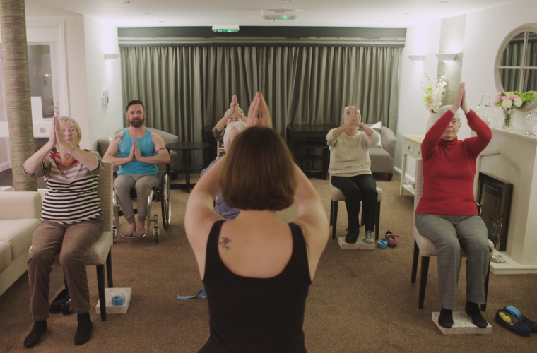 Presenter Kris taking part in a seated yoga session for older people