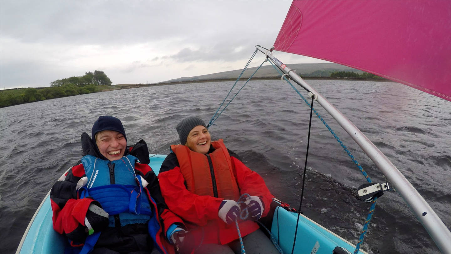 Hannah smiling with sailing buddy on sailing boat. 