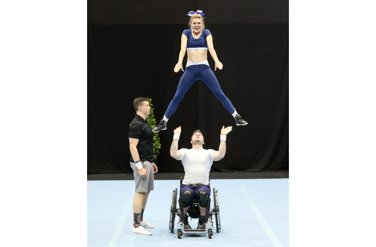 Rick lifting Chantal at a para-cheer competition. 