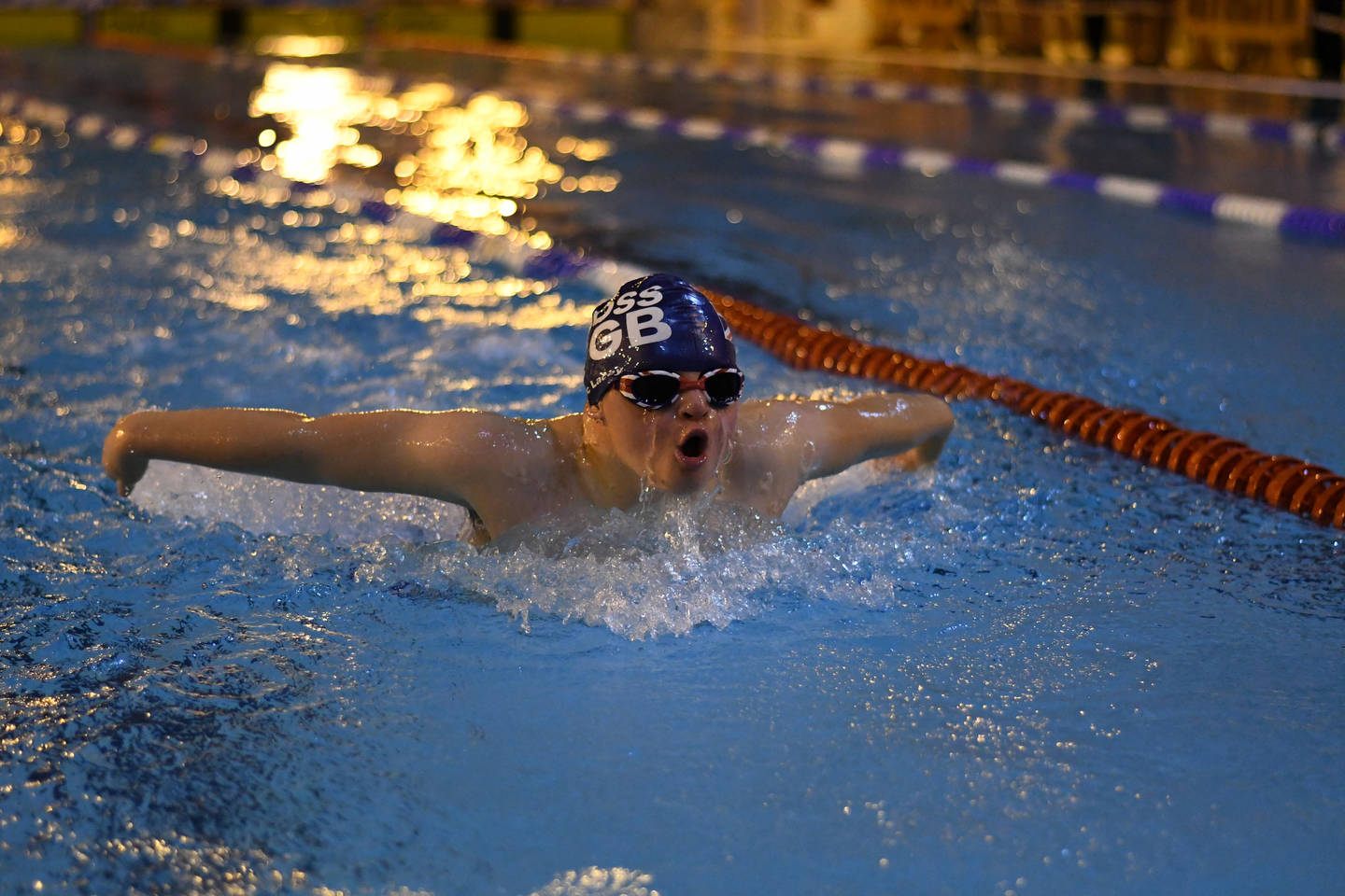 Zan swimming in pool with swimming cap and goggles on. 