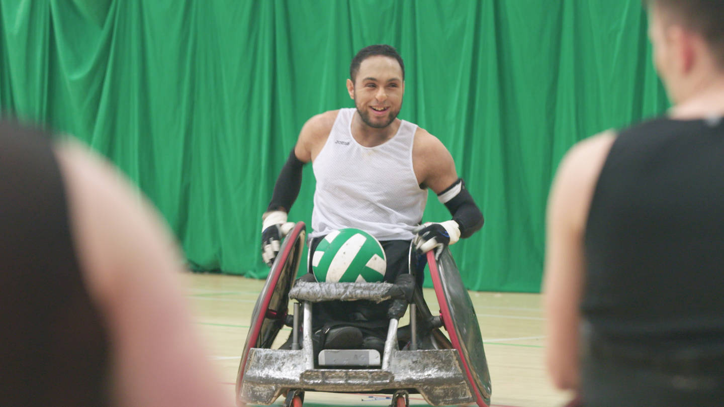 Wheelchair rugby player with ball smiling on court