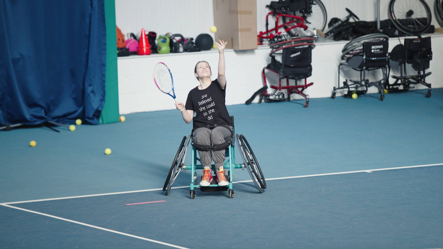 Wheelchair tennis player serving in game