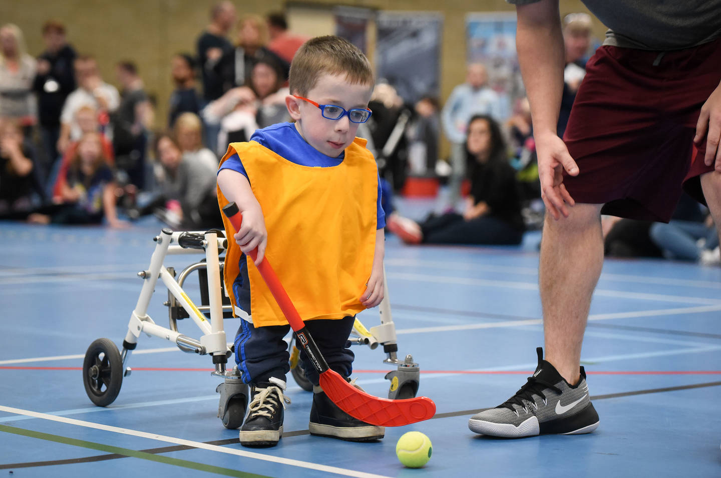 ung boy with dwarfism taking part in an indoor hockey game