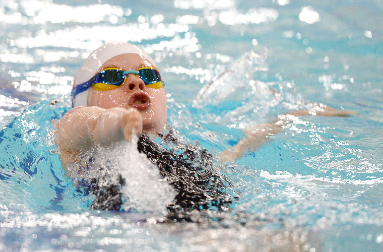 Young swimmer with upper limb impairment swimming backstroke in pool  